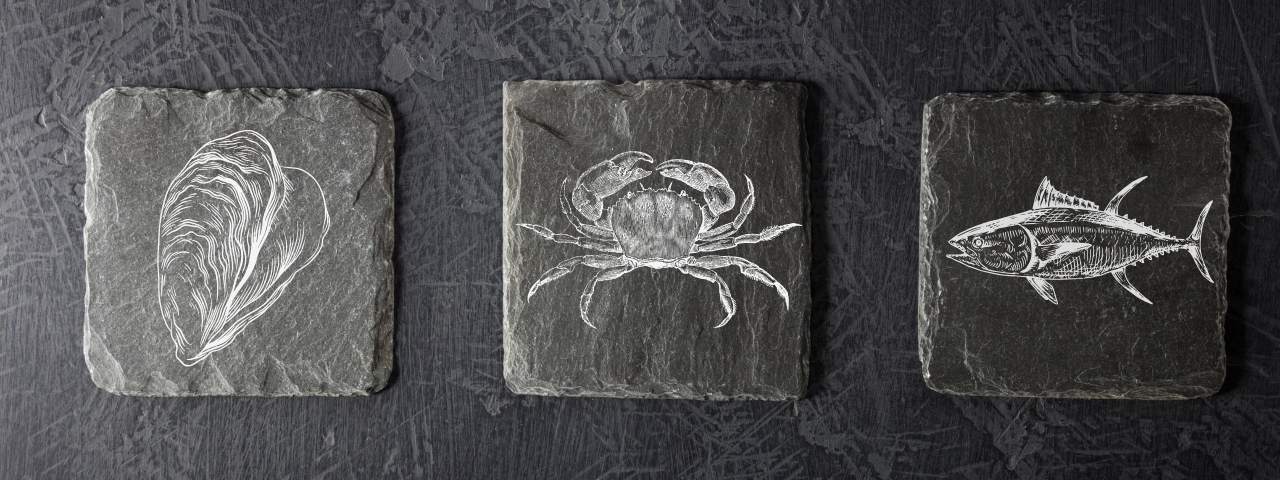 Sous-verres en ardoise gravés d’une huître, d’un crabe et d’un poisson