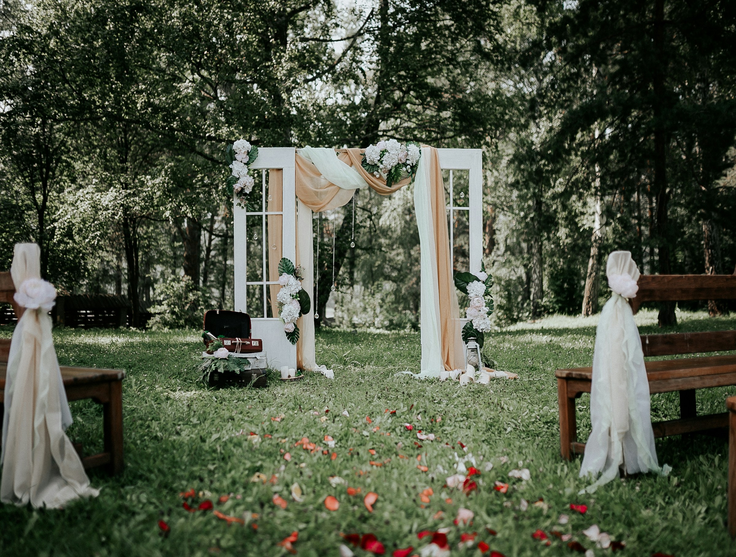 Arche de cérémonie de mariage en plein air, drapée de blanc et entourée de verdure
